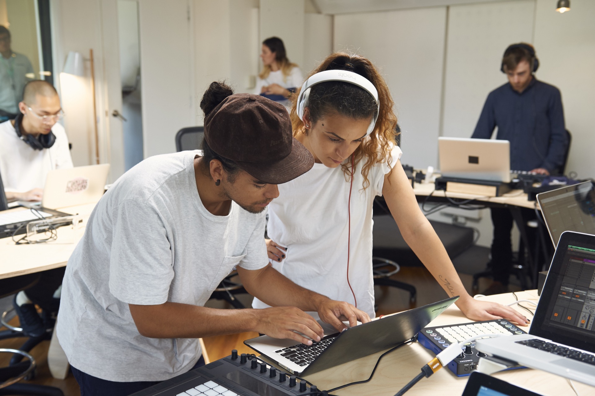 mentor and student refining a track together while other students work on their music