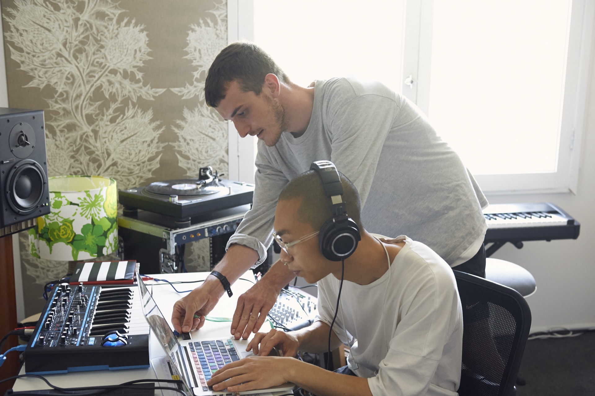 mentor and student developing a music composition in the studio using ableton live and samples from a vinyl record.