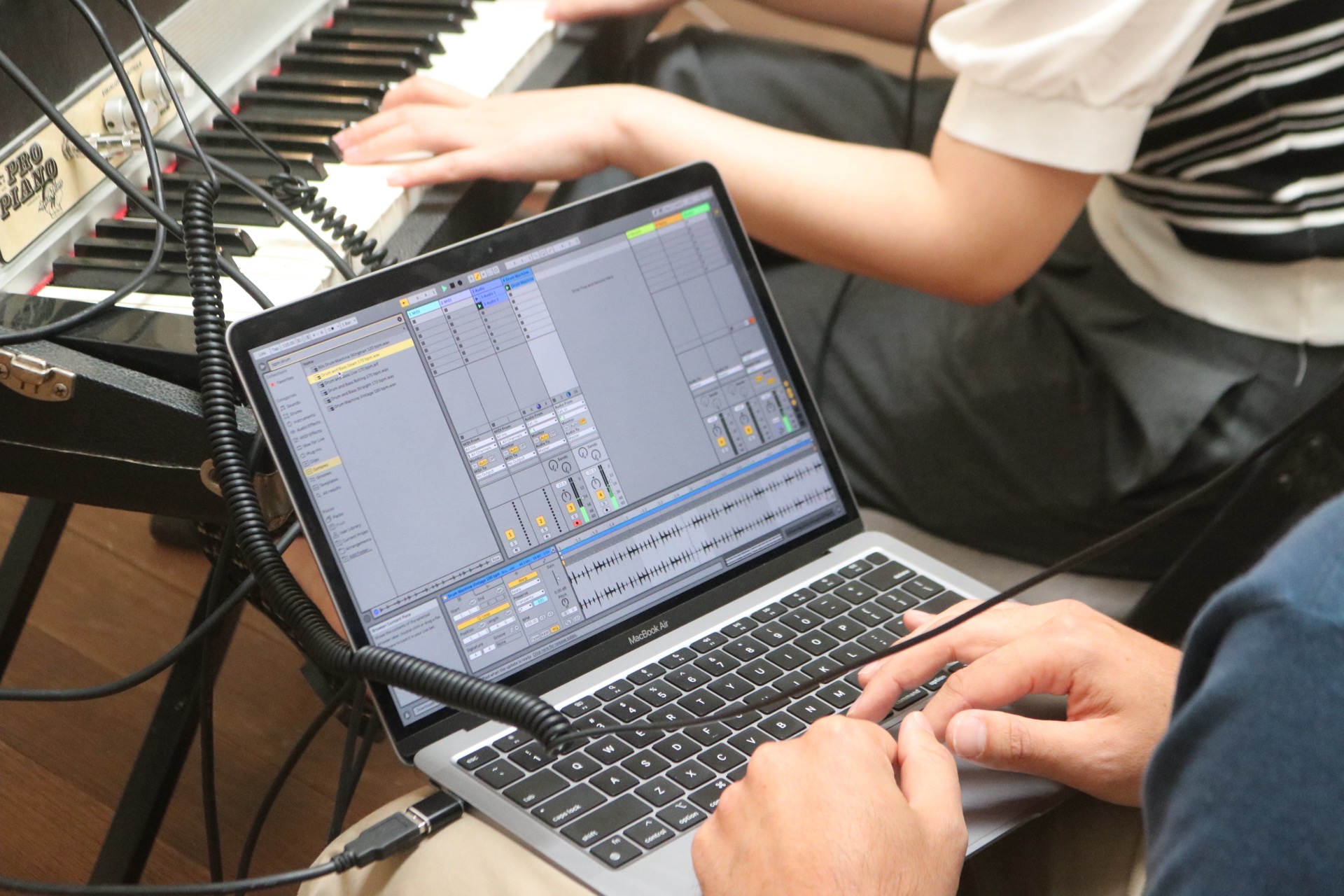 students working on a track together at Liveschool Sydney with one producer recording another playing keys.
