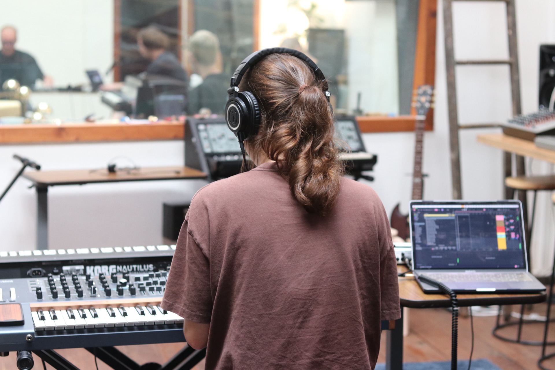 student producing music in the studio with Ableton Live, an Arturia Polybrute synth and Roland SH-5.