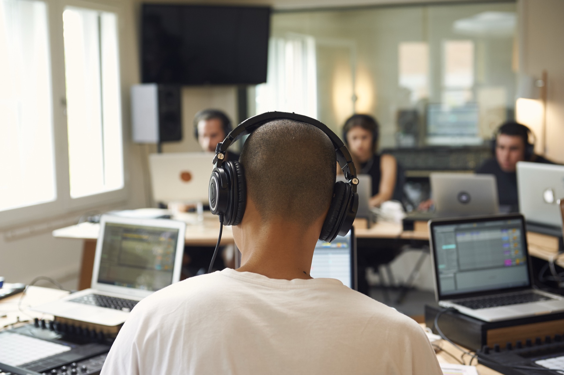 students in headphones during class at Liveschool Sydney making music with Ableton Live on laptops.