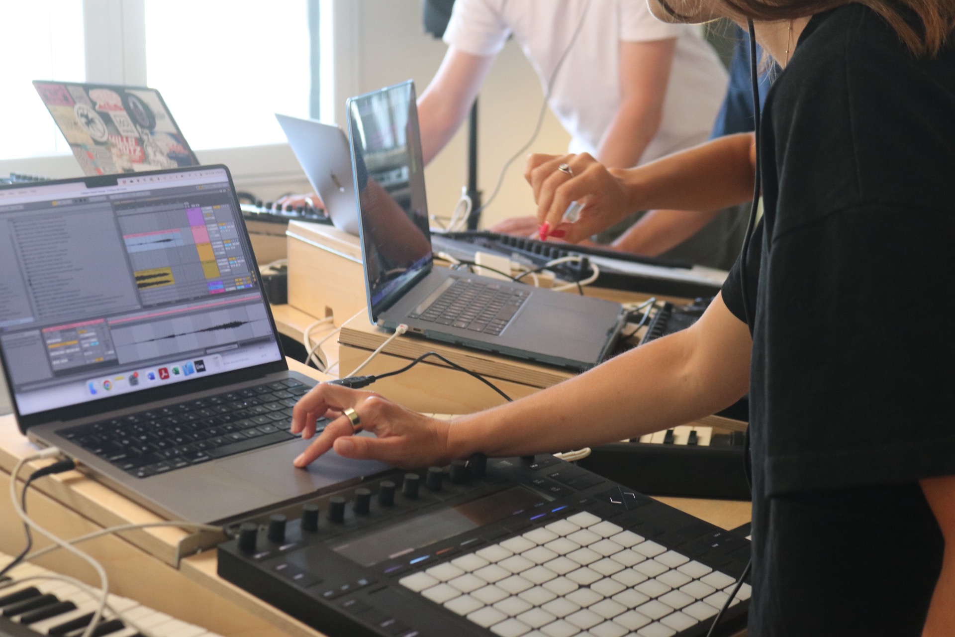 students producing music in class with Ableton Live and Push in a sunlit studio.