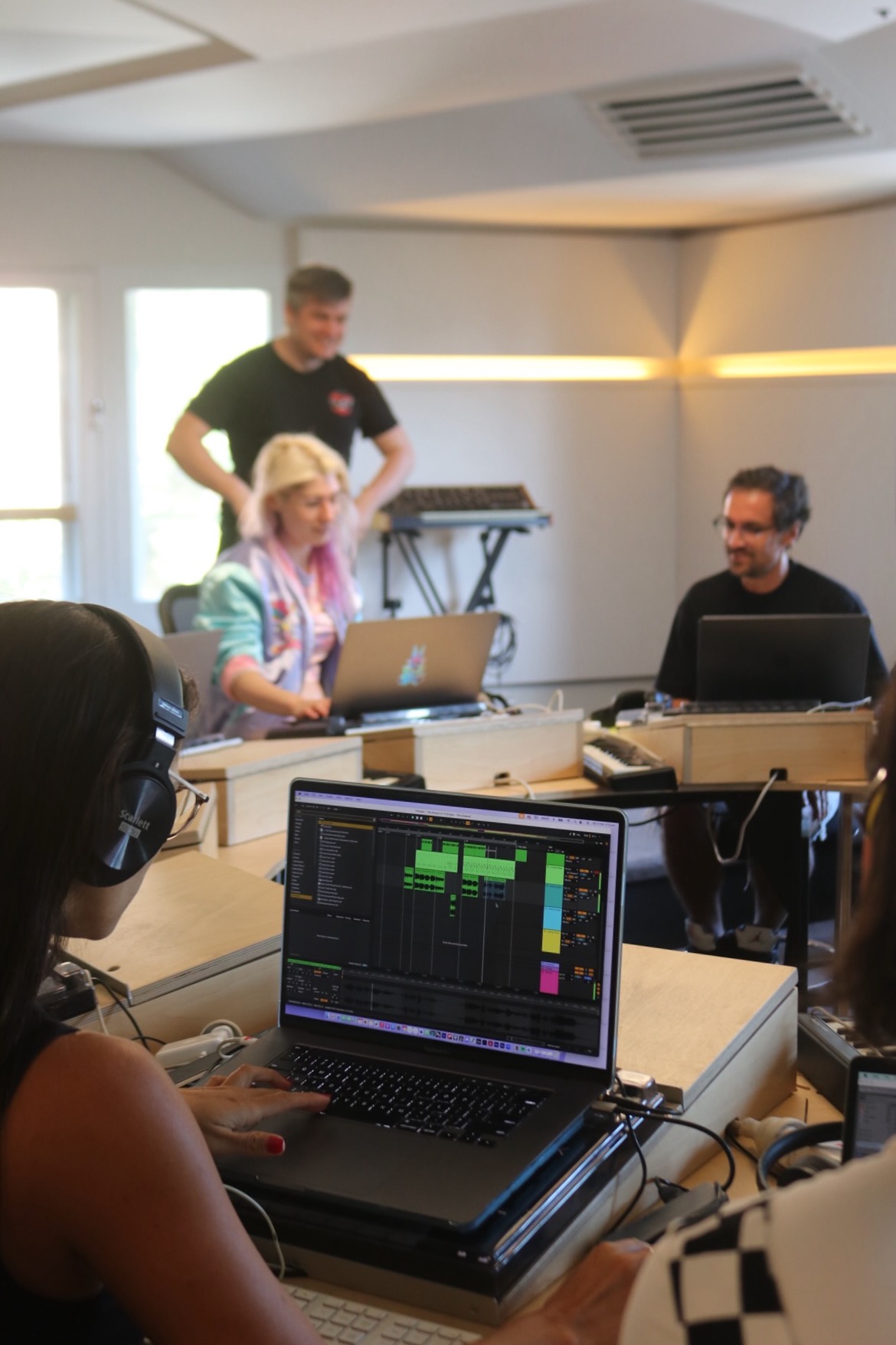 student making music in a studio classroom while other students collaborate on a track