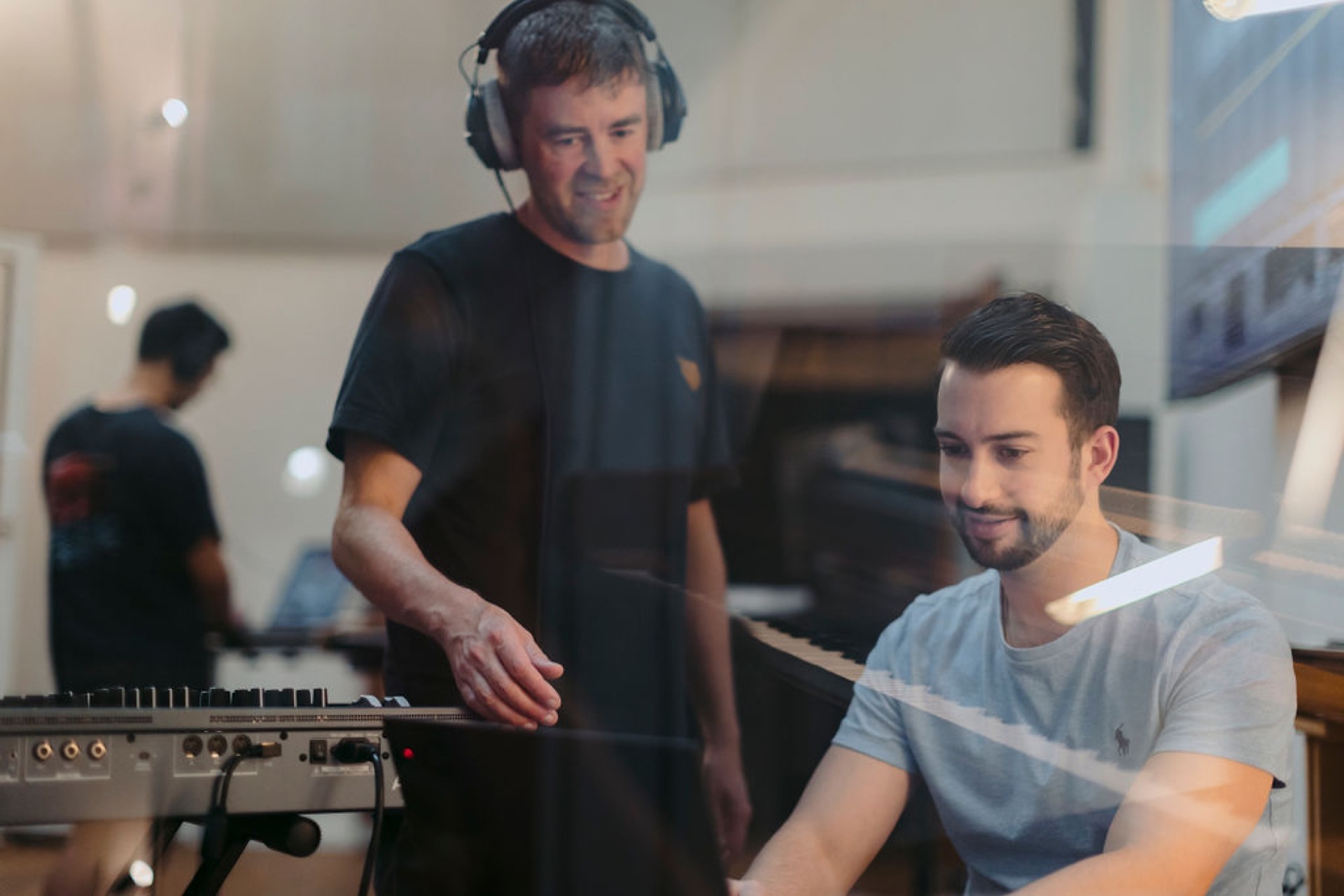 Mentor guiding a student during a music production session in a studio classroom.